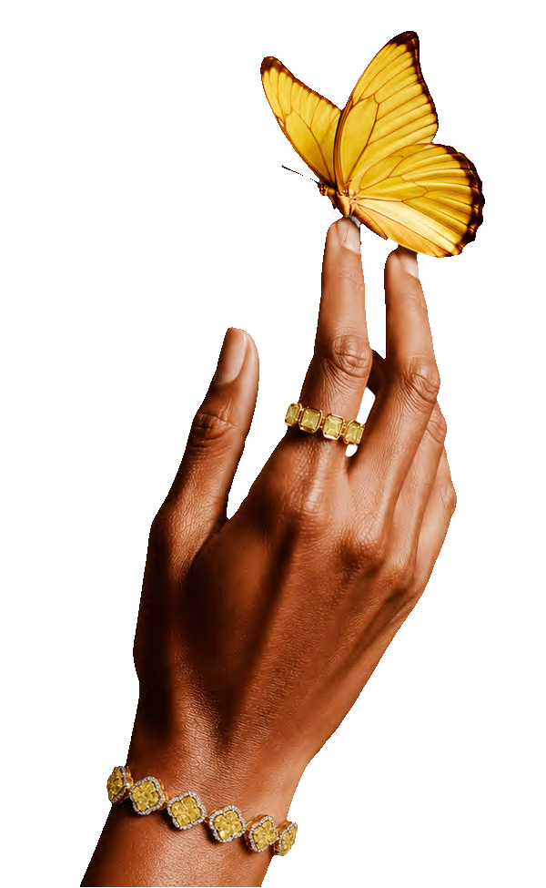 A hand wearing yellow diamond jewellery, a butterfly resting on a fingertip